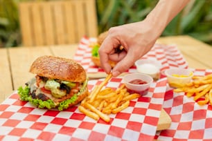 a person is holding a fork over a hamburger and french fries