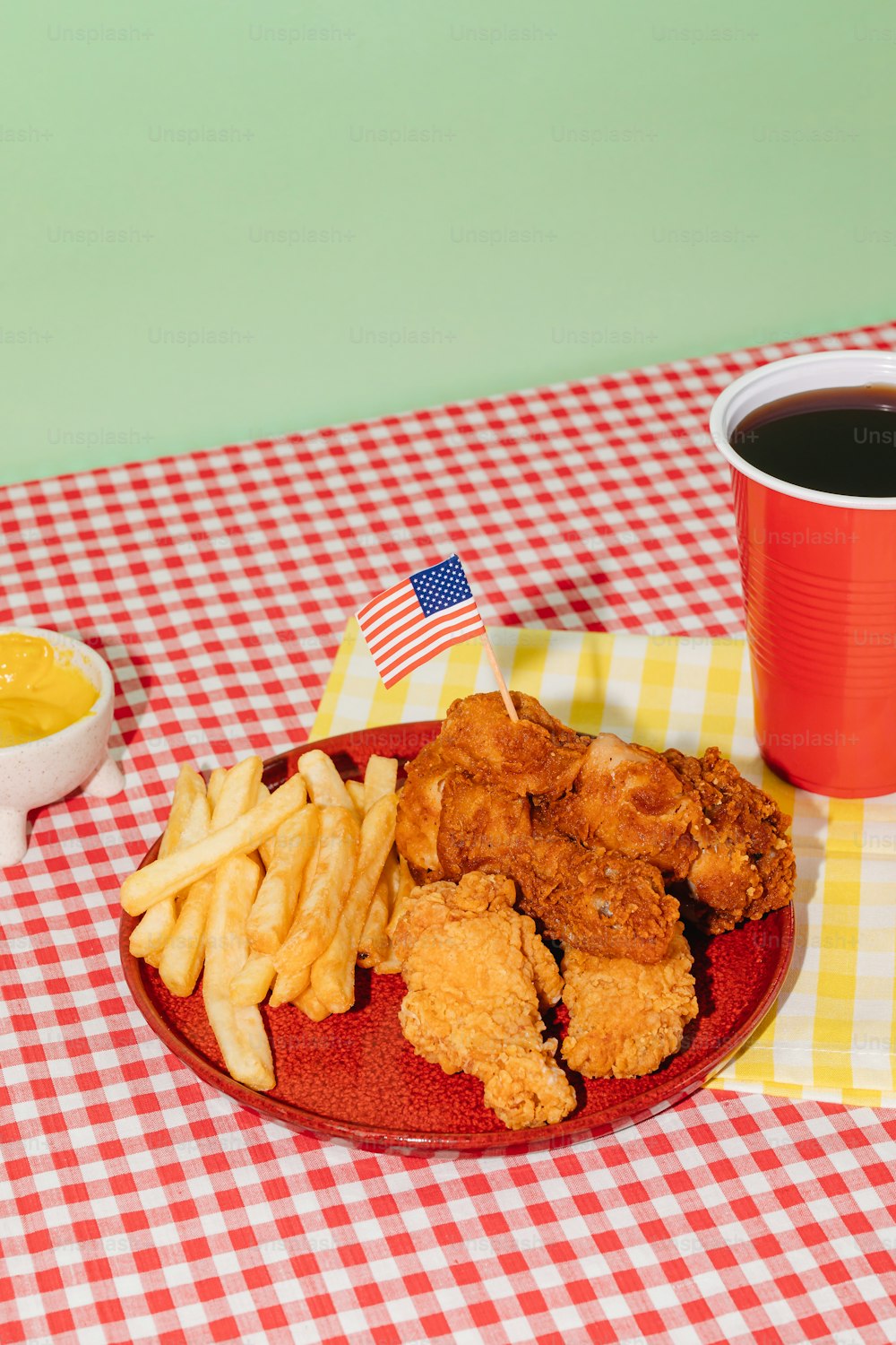 a plate of fried chicken, french fries and a bowl of mustard