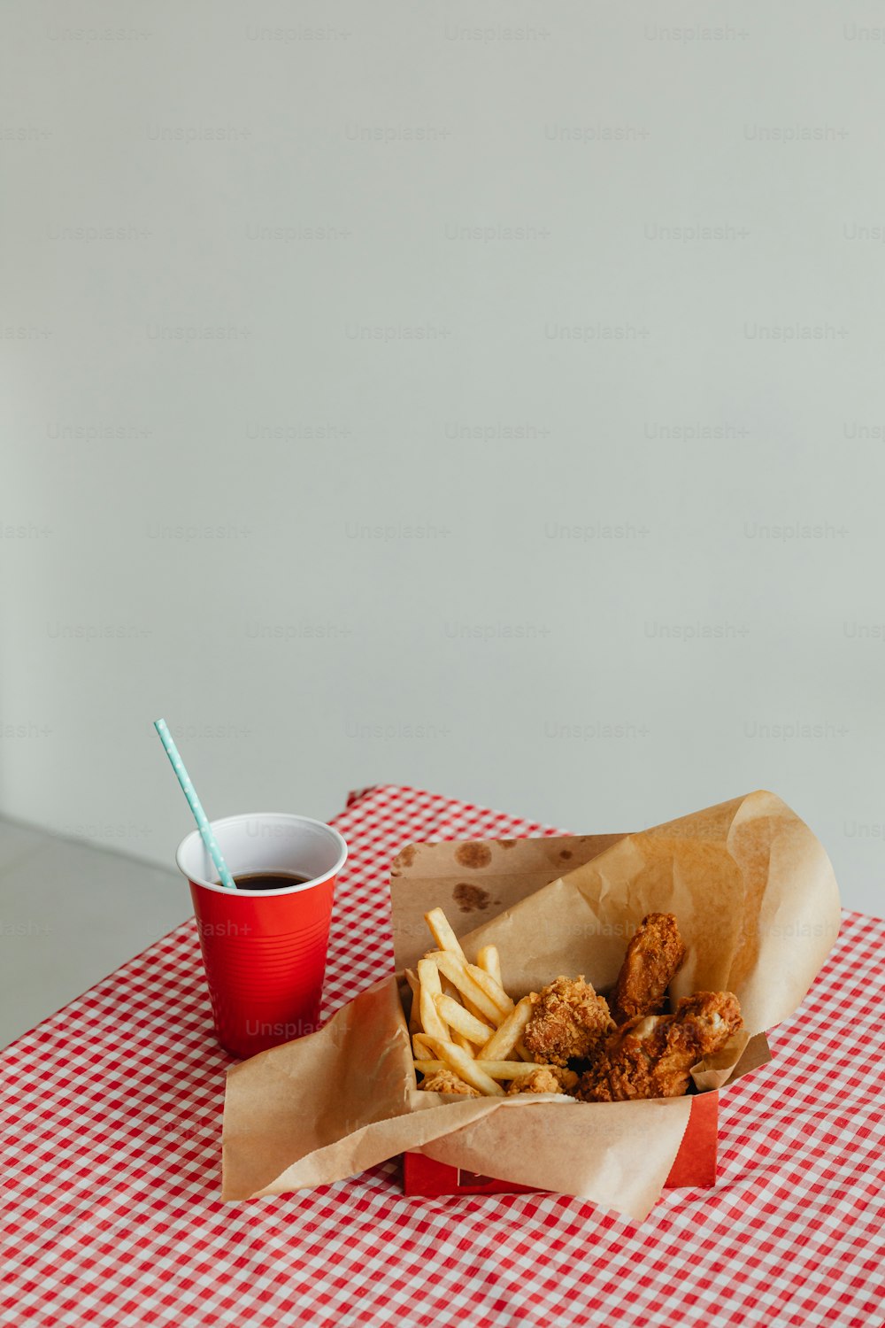una mesa a cuadros rojos y blancos con una canasta de papas fritas y una taza de