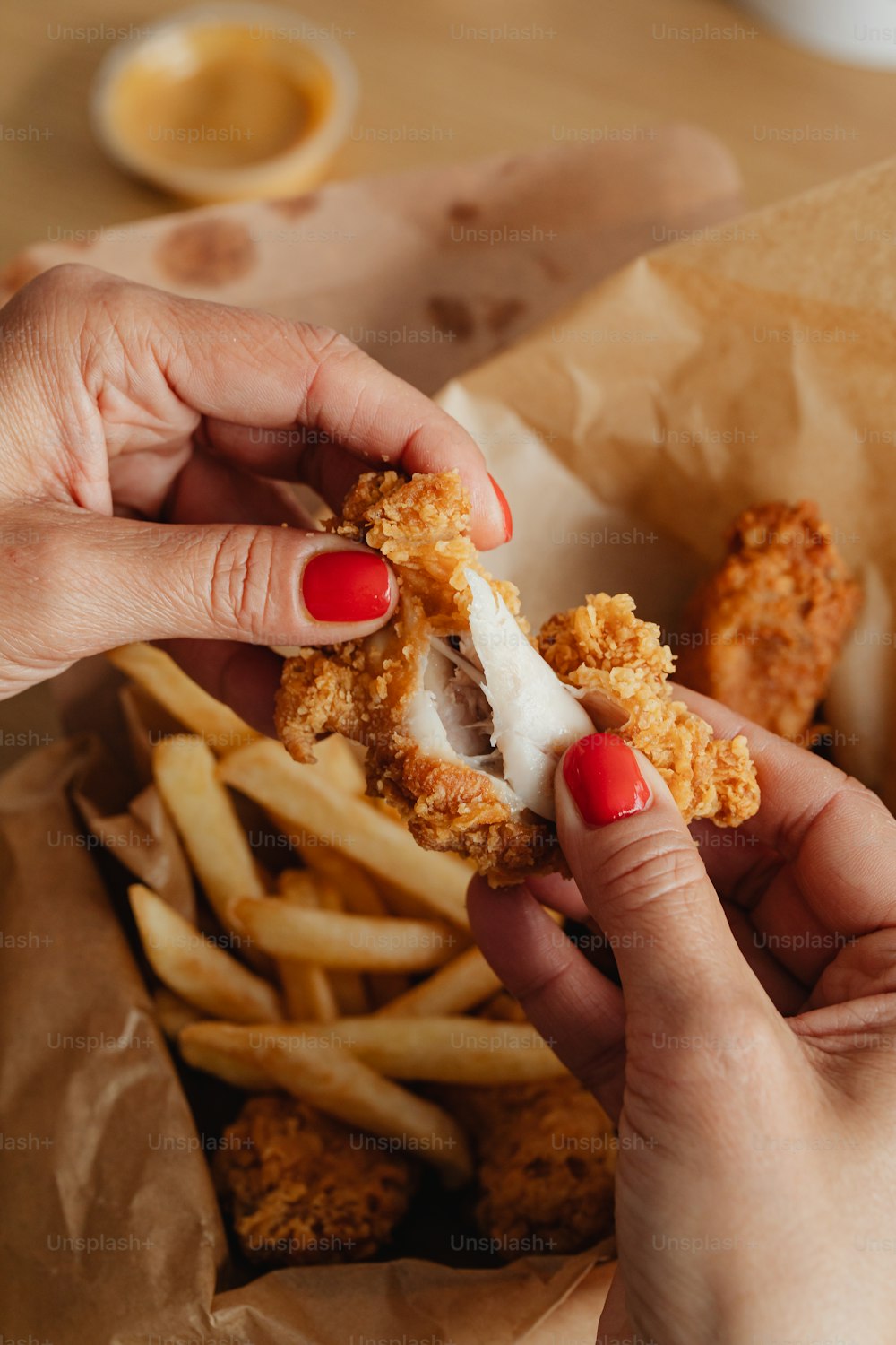 a woman is holding a fried chicken sandwich and french fries
