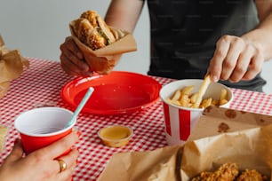 a person eating a hot dog and fries at a table