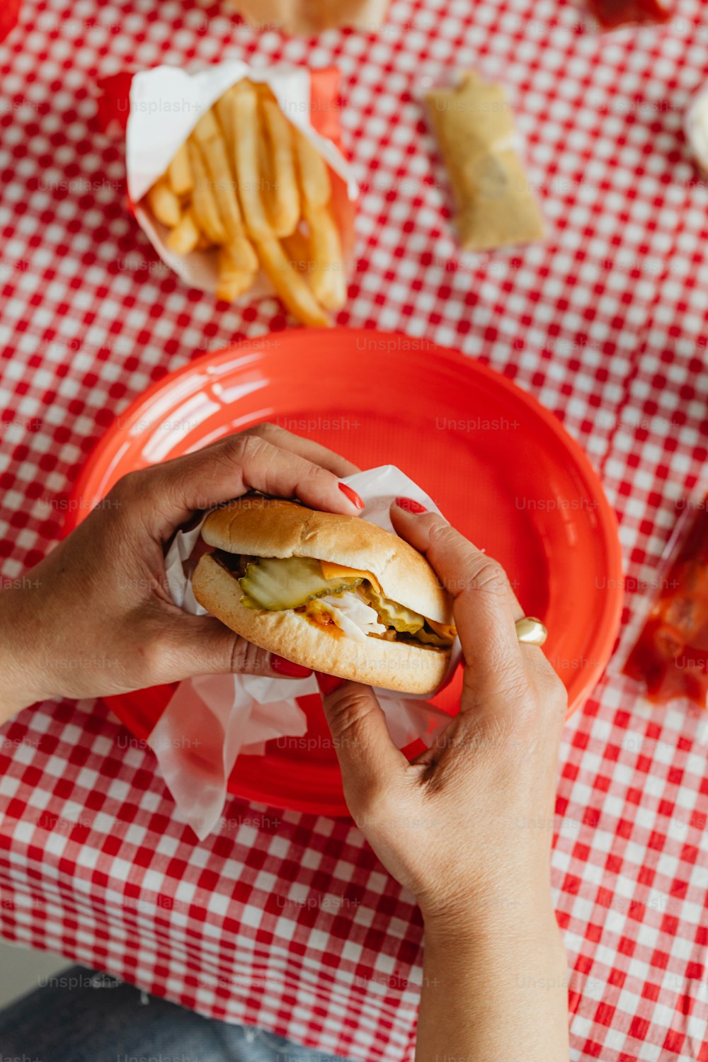 a person is holding a sandwich on a red plate