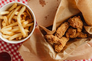 a bowl of fries next to a basket of fried chicken