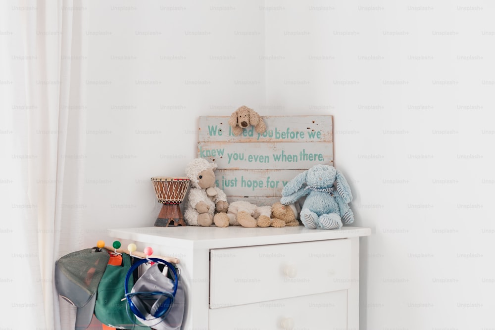 a white chest of drawers with stuffed animals on top of it