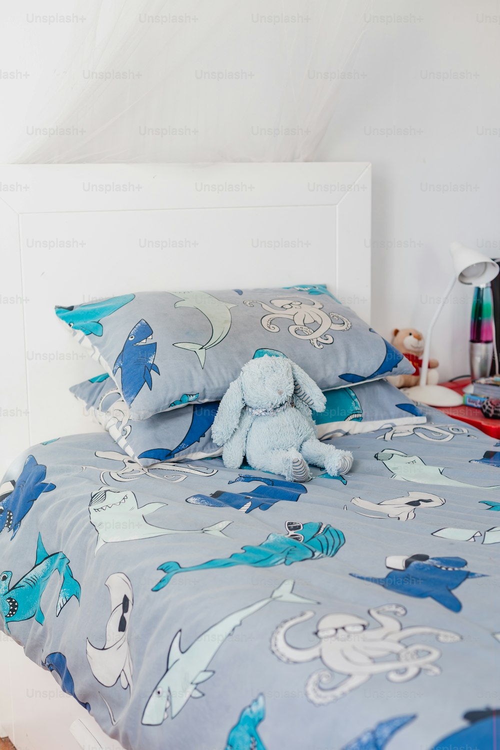 una cama con edredón azul y un peluche azul