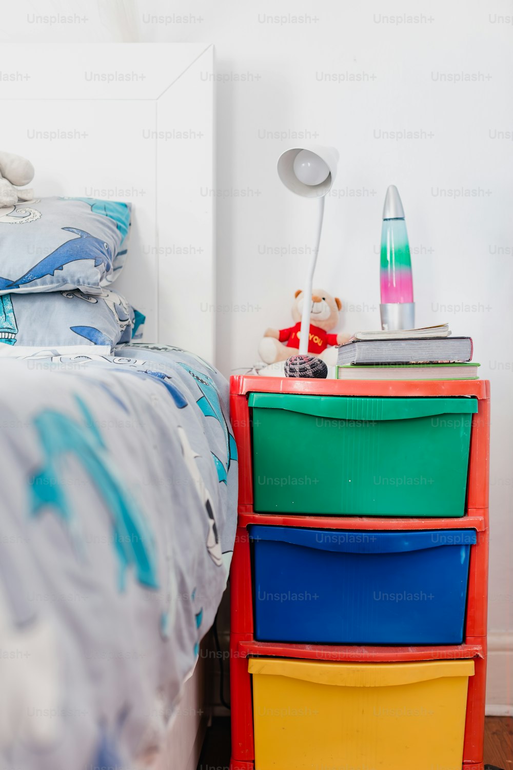 une commode colorée à côté d’un lit dans une chambre