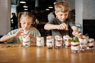 a boy and a girl making desserts at a table