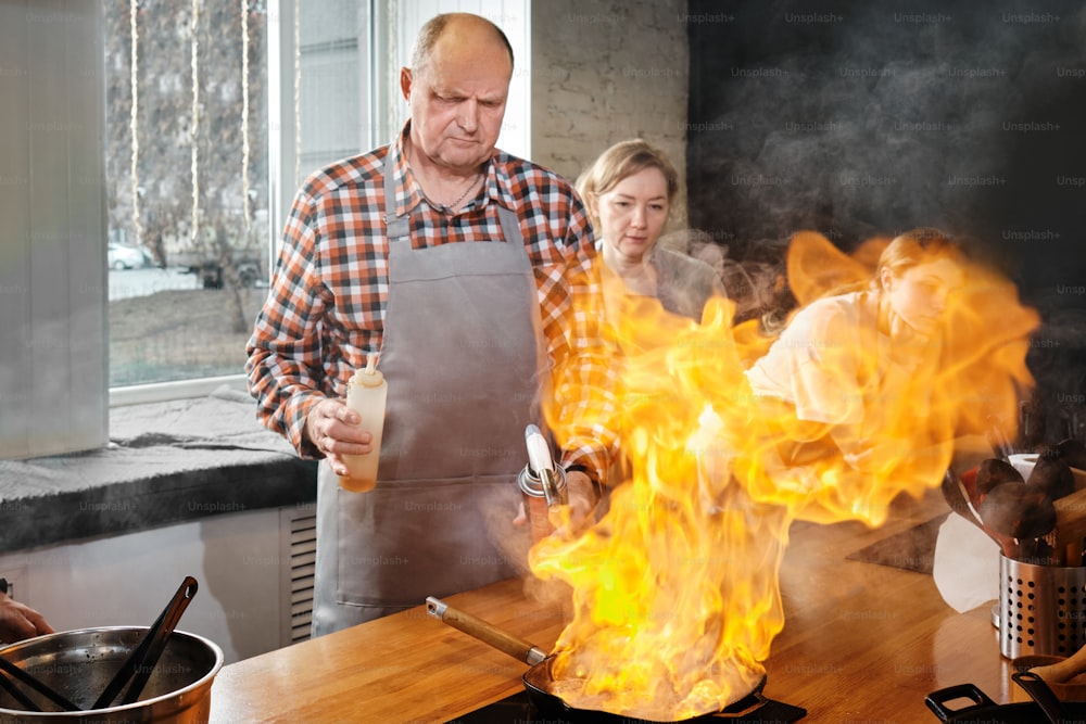 a man and a woman cooking in a kitchen on fire