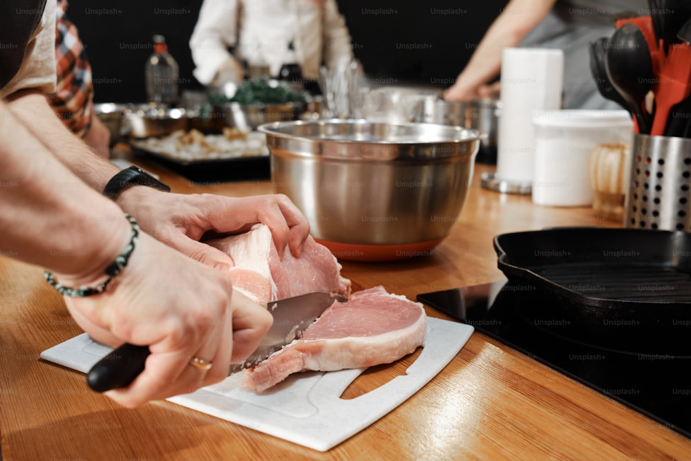 a person cutting up a piece of meat on a cutting board