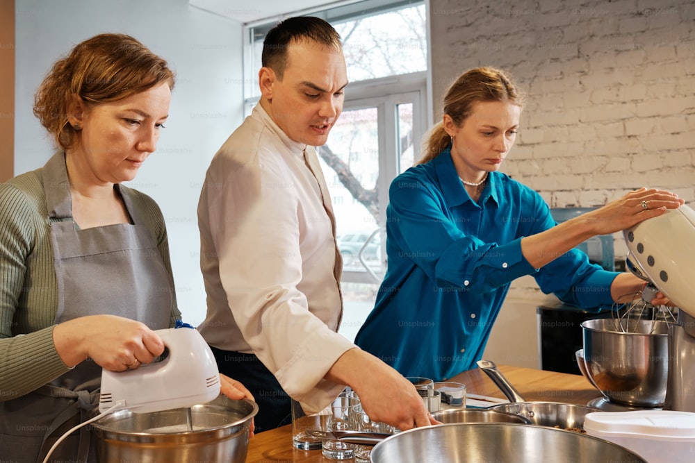 a man and two women in a kitchen preparing food