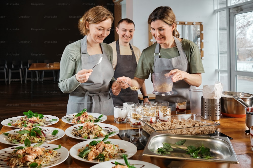 three women in aprons preparing food in a kitchen