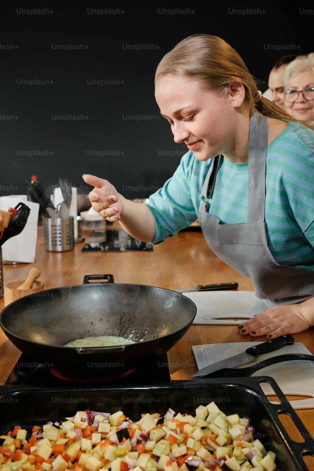 a woman cooking food in a pan on a table
