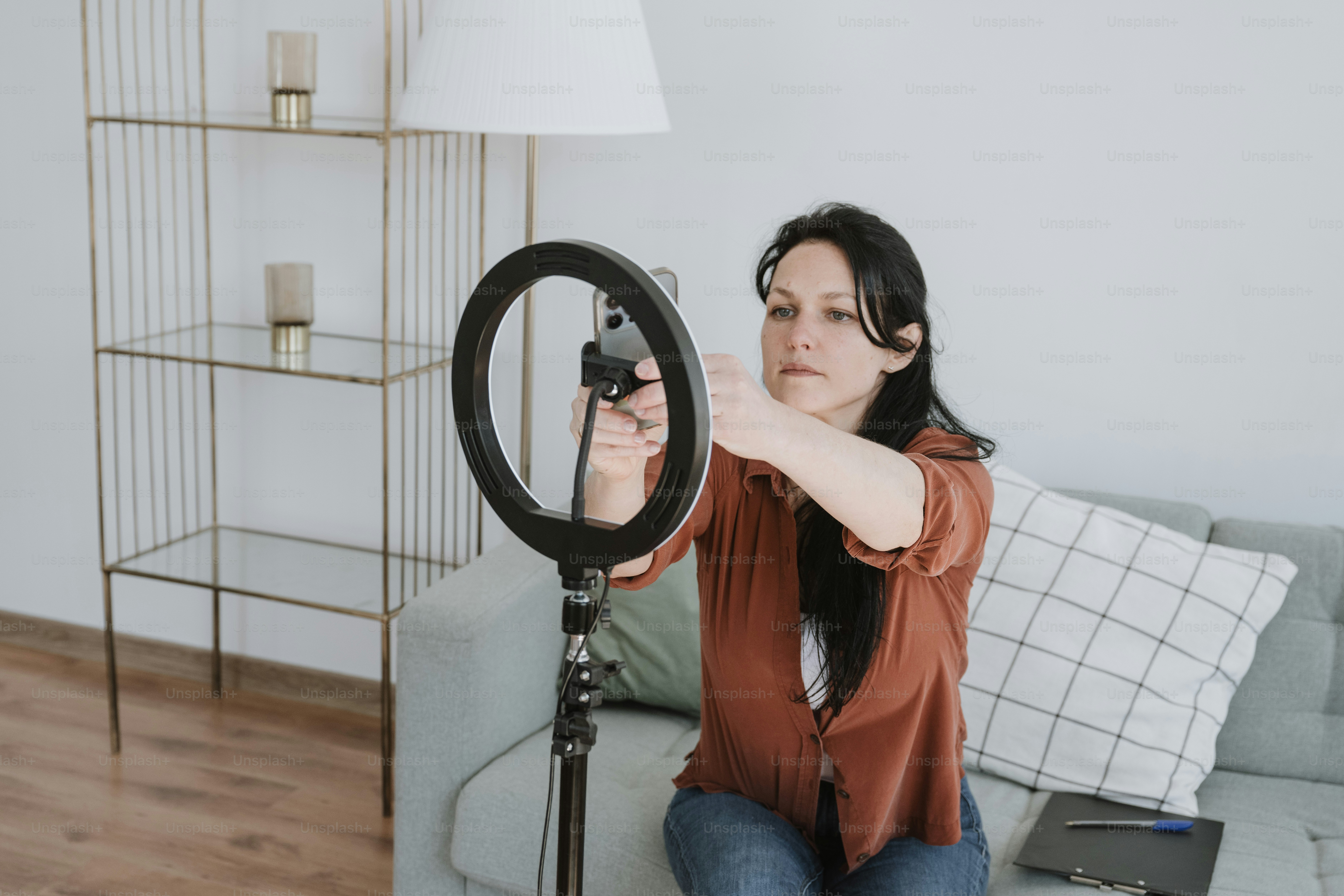 Seorang wanita duduk di sofa sambil memegang kamera