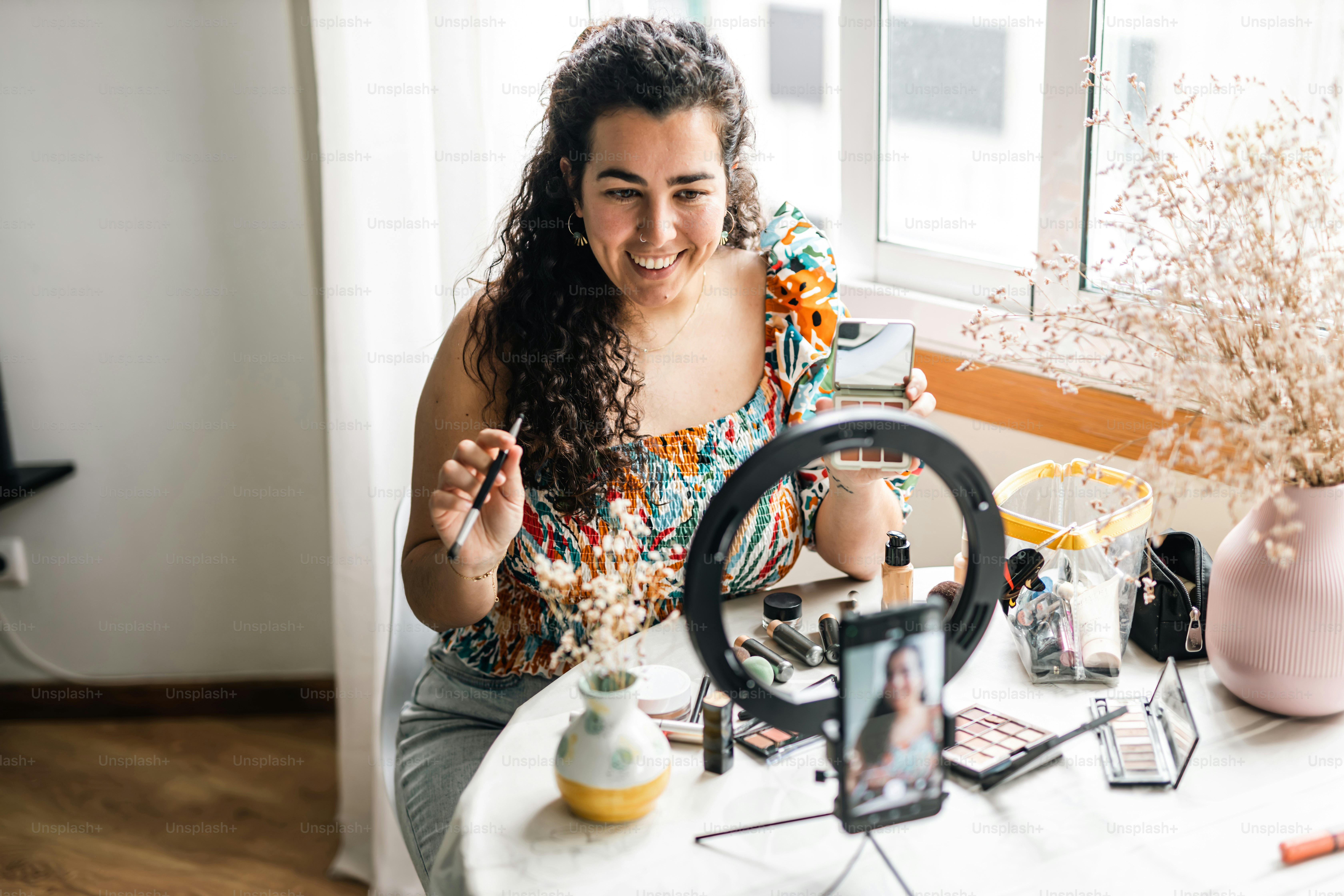a woman sitting at a table with makeup and a mirror
