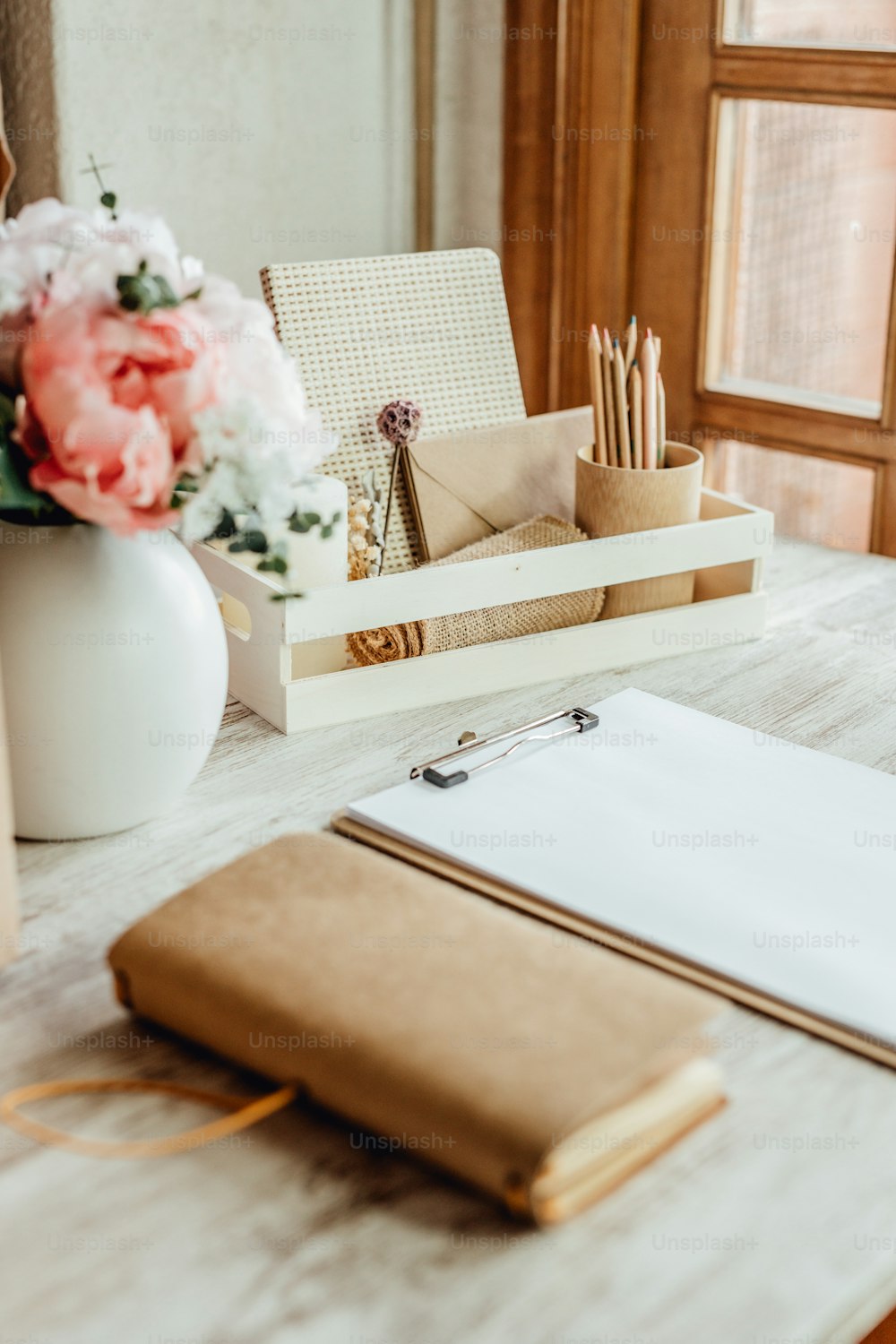 un bureau avec un bloc-notes, un porte-stylo et un vase de fleurs