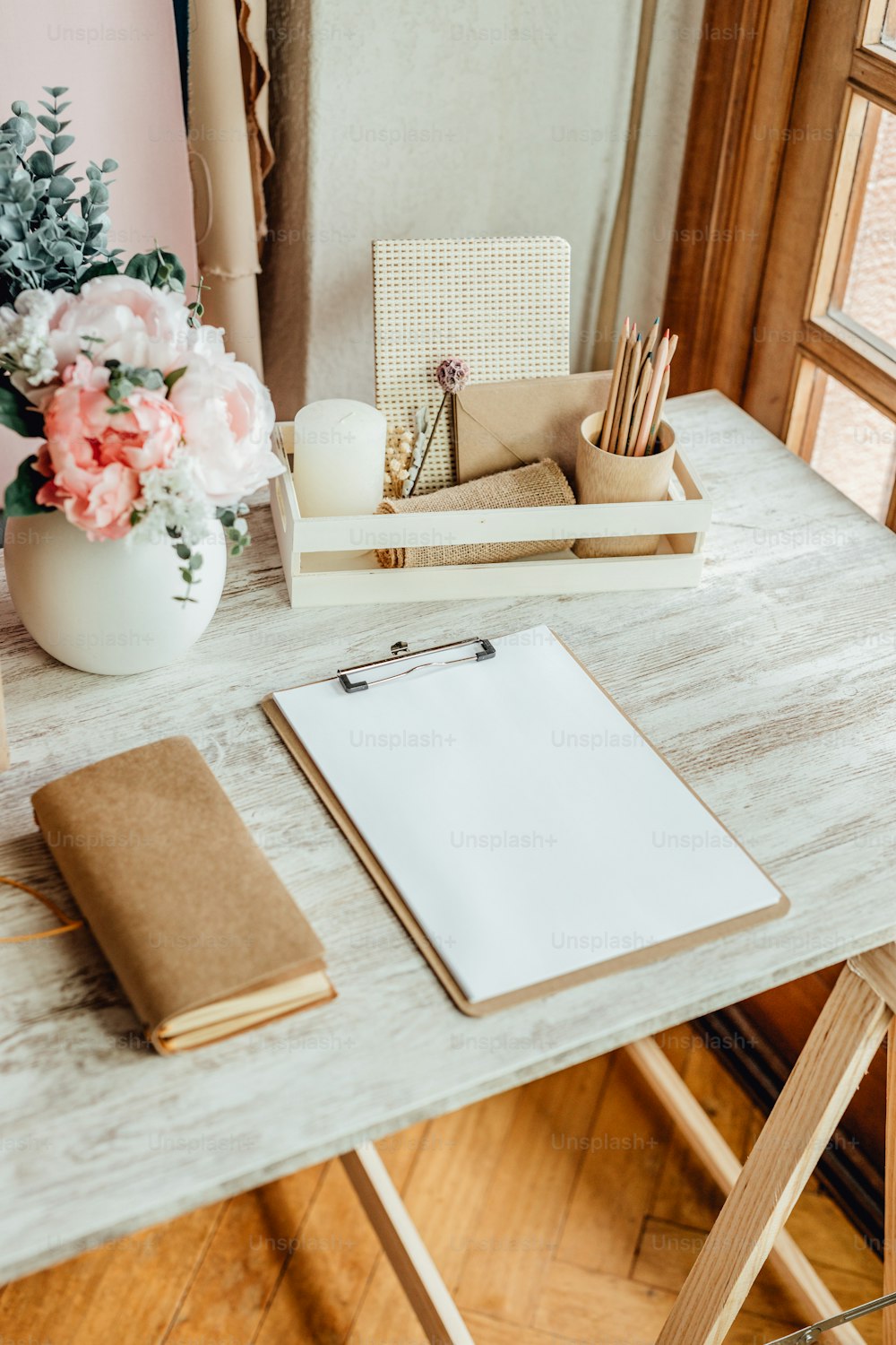 a wooden table topped with a notebook and flowers