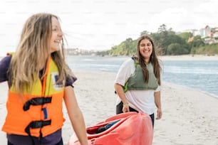 two women walking on the beach with a life jacket on