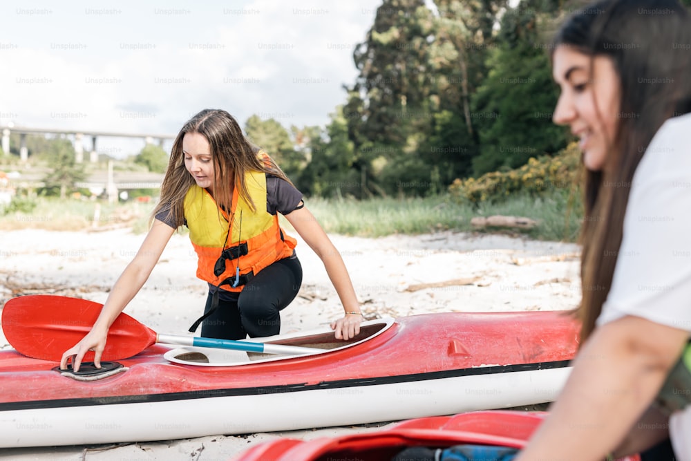 a woman standing next to a red and white kayak