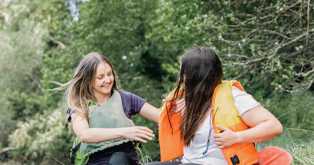 Two women sitting on a raft in the grass photo – Lifejacket Image on ...