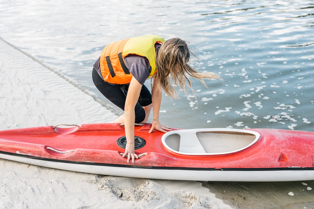 a woman bending over on top of a red surfboard