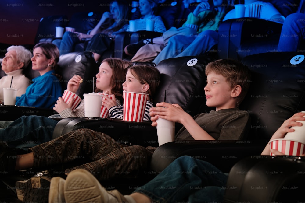 um grupo de pessoas sentadas em uma fileira assistindo a um filme