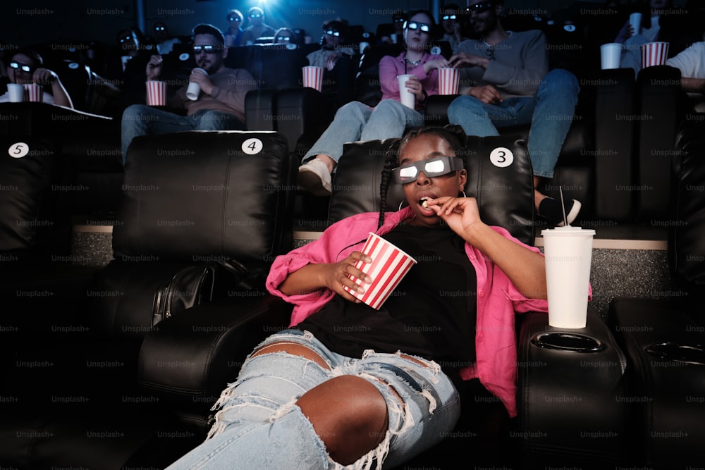 a woman sitting in a movie theater holding a popcorn