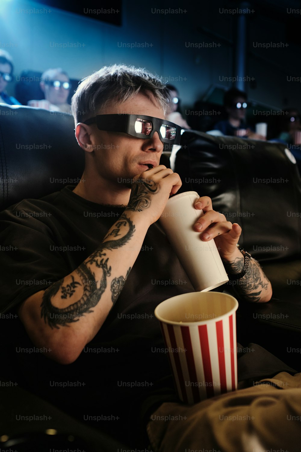 a man sitting in a chair with a cup of popcorn