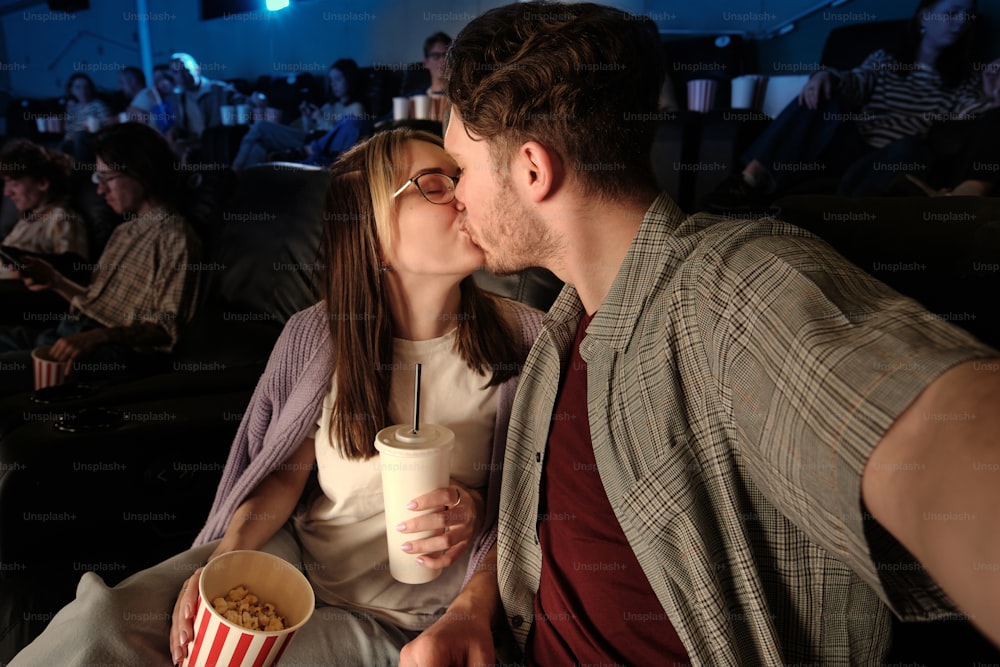 a man and a woman kissing while watching a movie