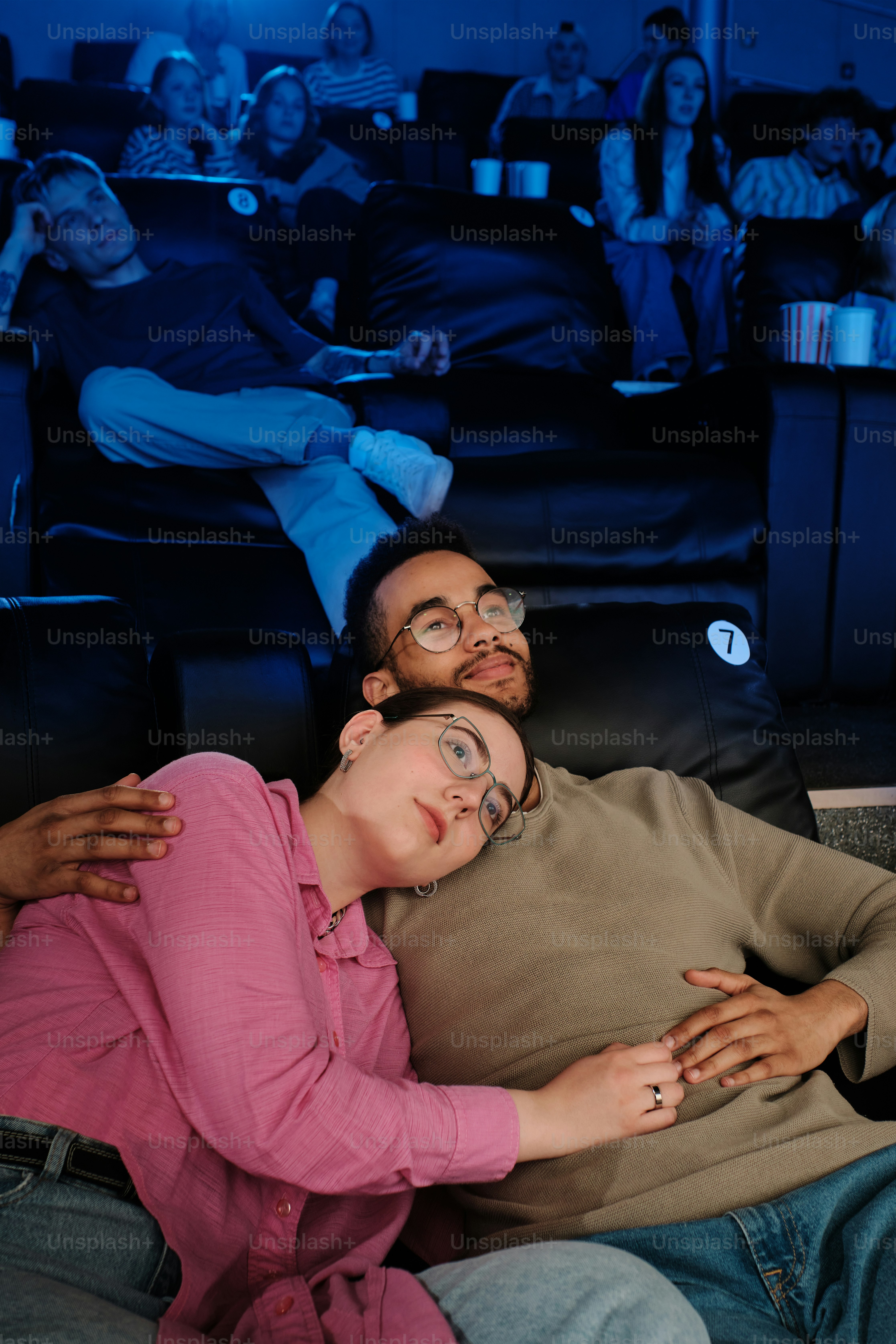 a couple half-lying at a movie theatre with automatic upholstered seats