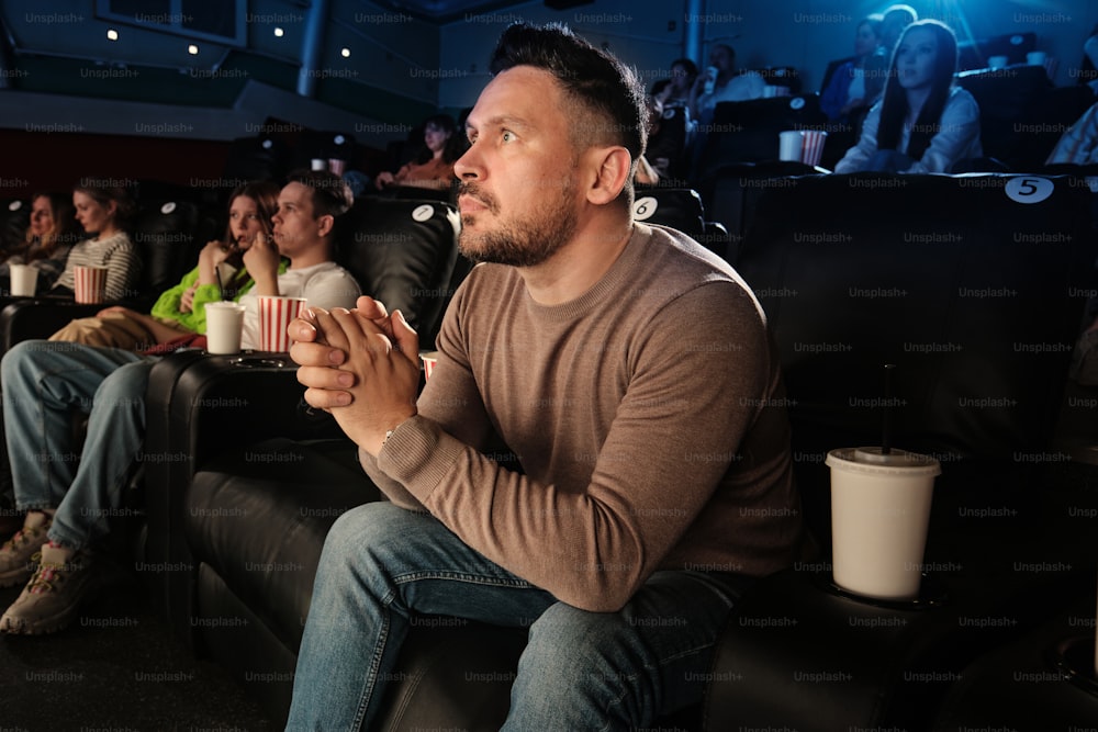 a man sitting on a black couch in front of a crowd of people