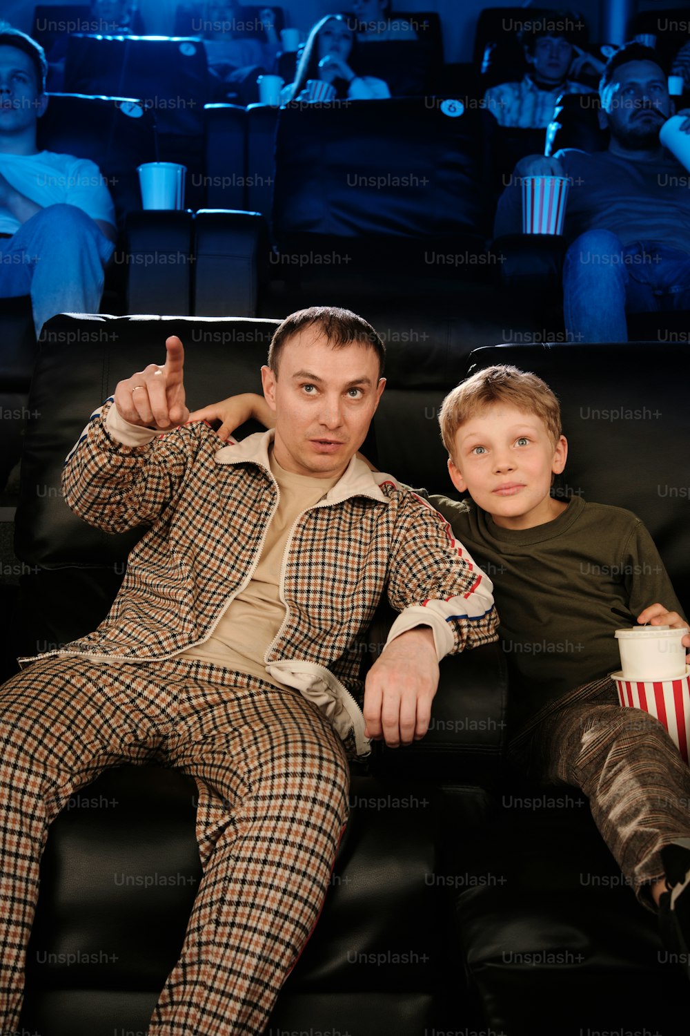 Un hombre y un niño sentados en un sofá viendo una película