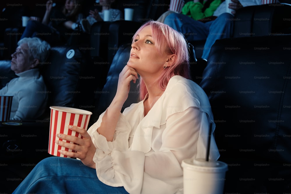 uma mulher com cabelo rosa sentada em um teatro