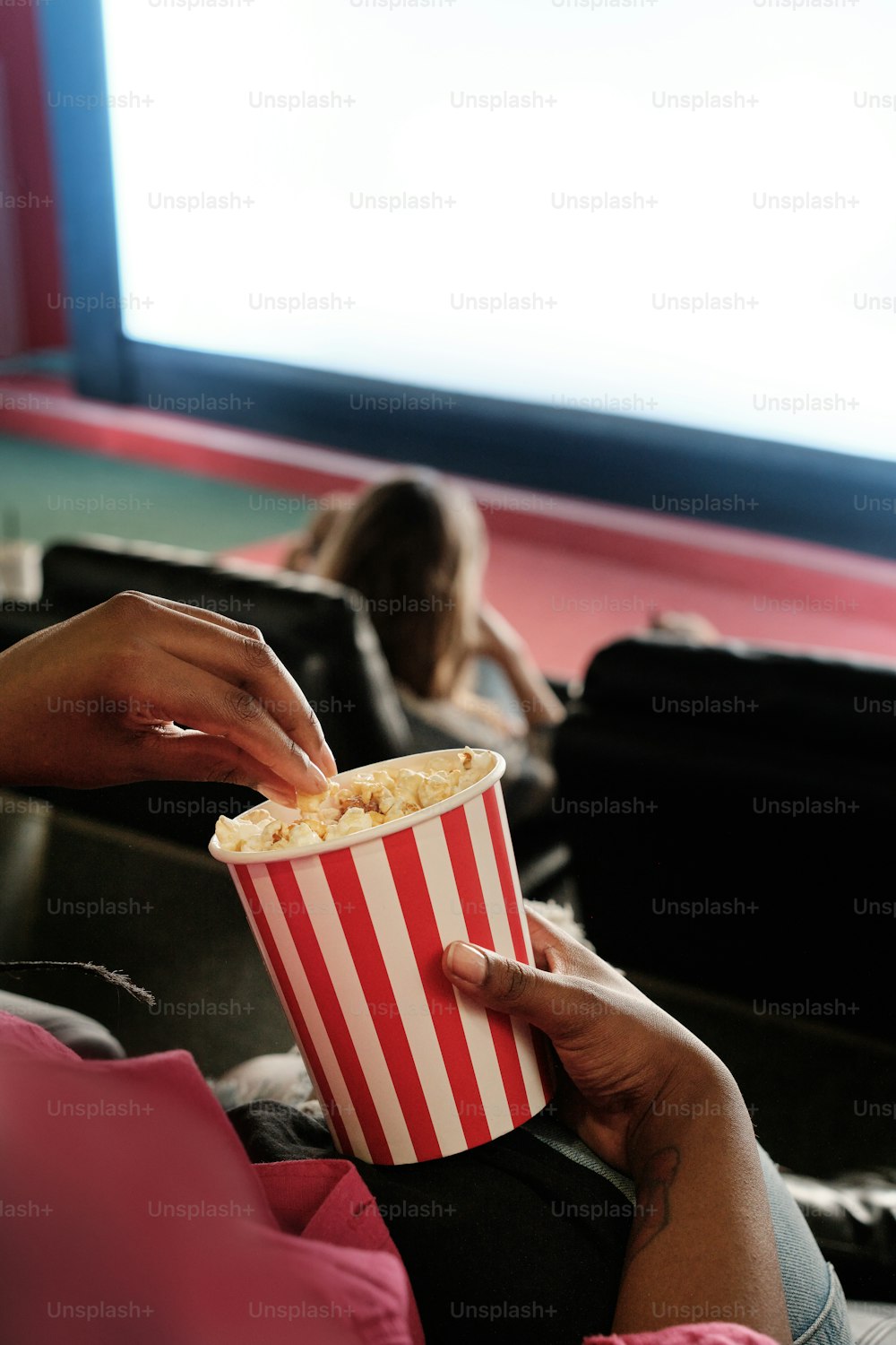 a person holding a cup of popcorn in their hand