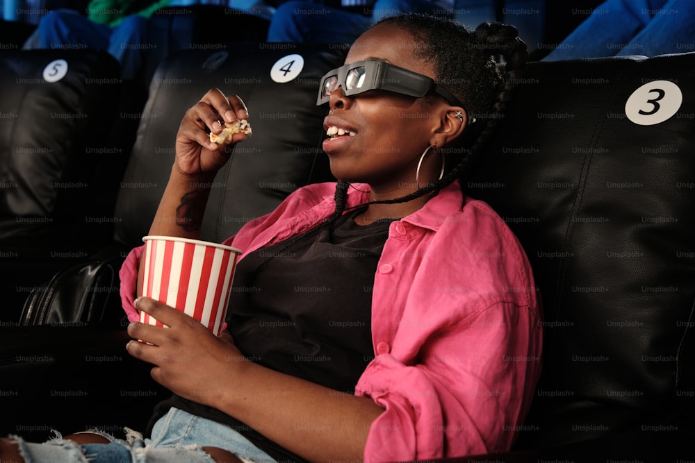 a woman sitting in a chair with a cup of popcorn