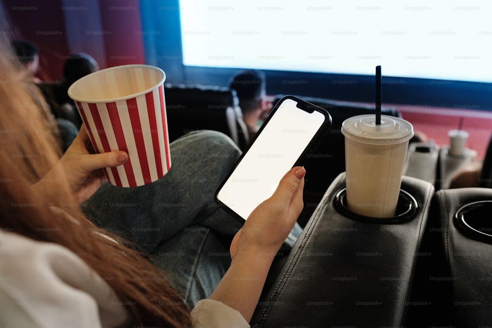 Una mujer sosteniendo un teléfono inteligente y una taza de café
