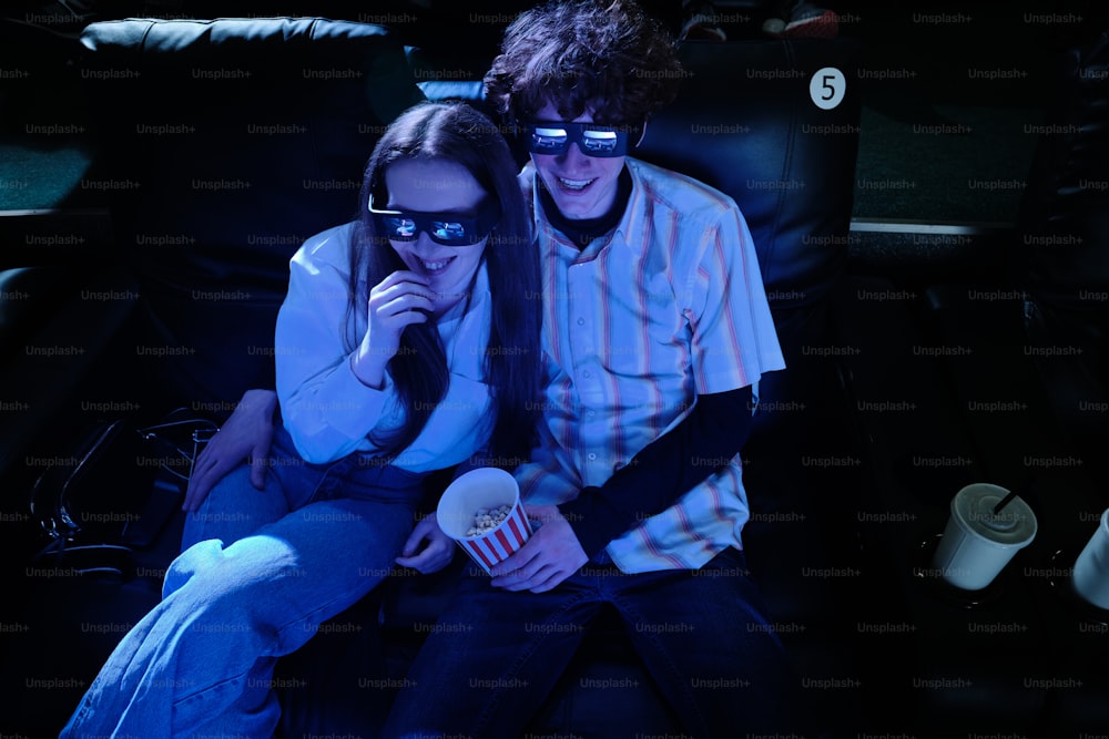 a man and a woman sitting in a chair watching a movie