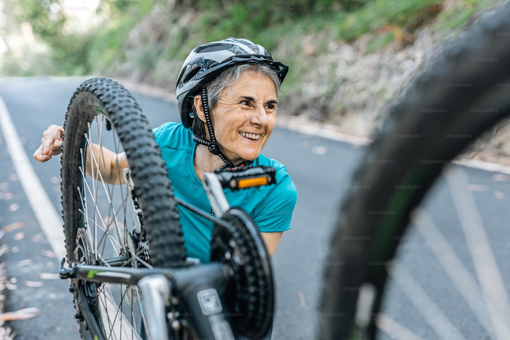 a woman with a helmet is holding a bicycle tire