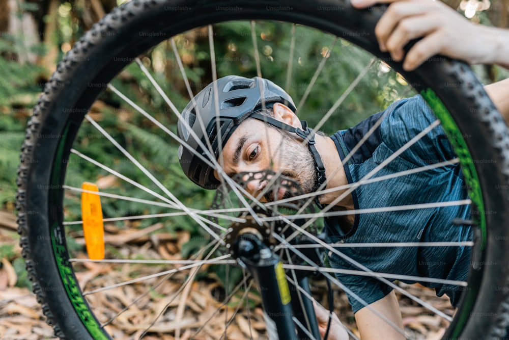 Un hombre sosteniendo una rueda de bicicleta con la cara pintada