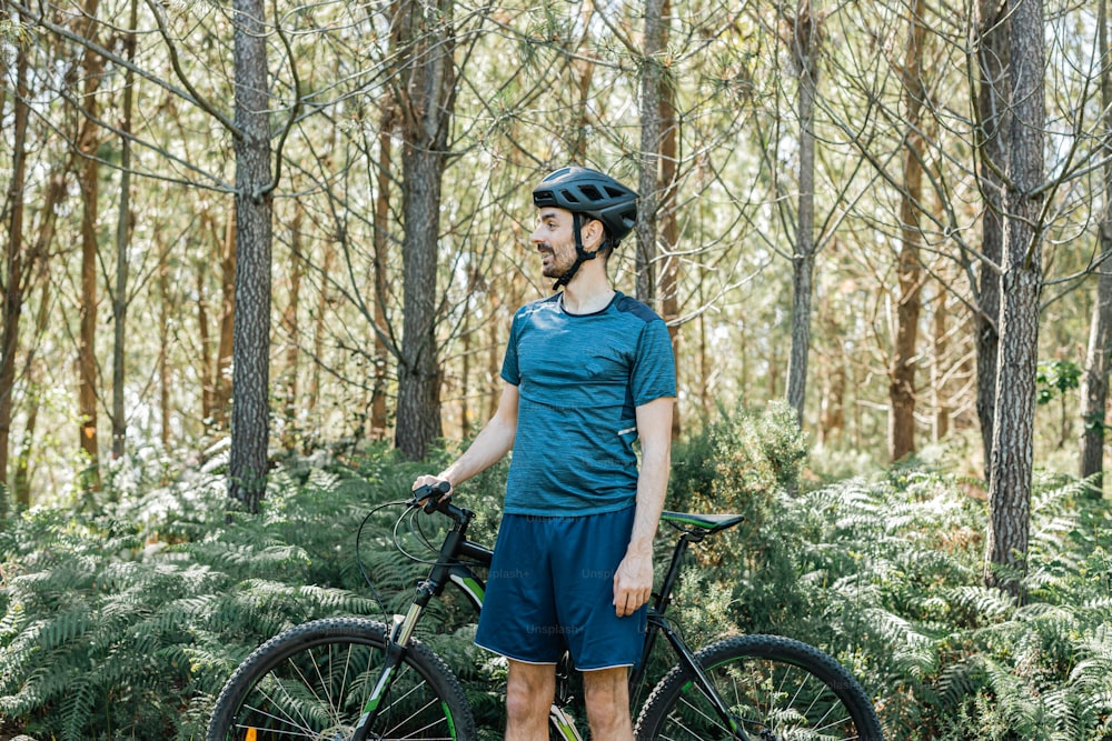 um homem parado ao lado de uma bicicleta na floresta