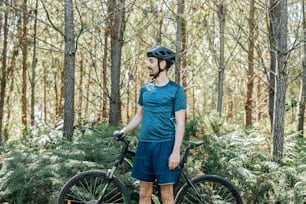 a man standing next to a bike in the woods