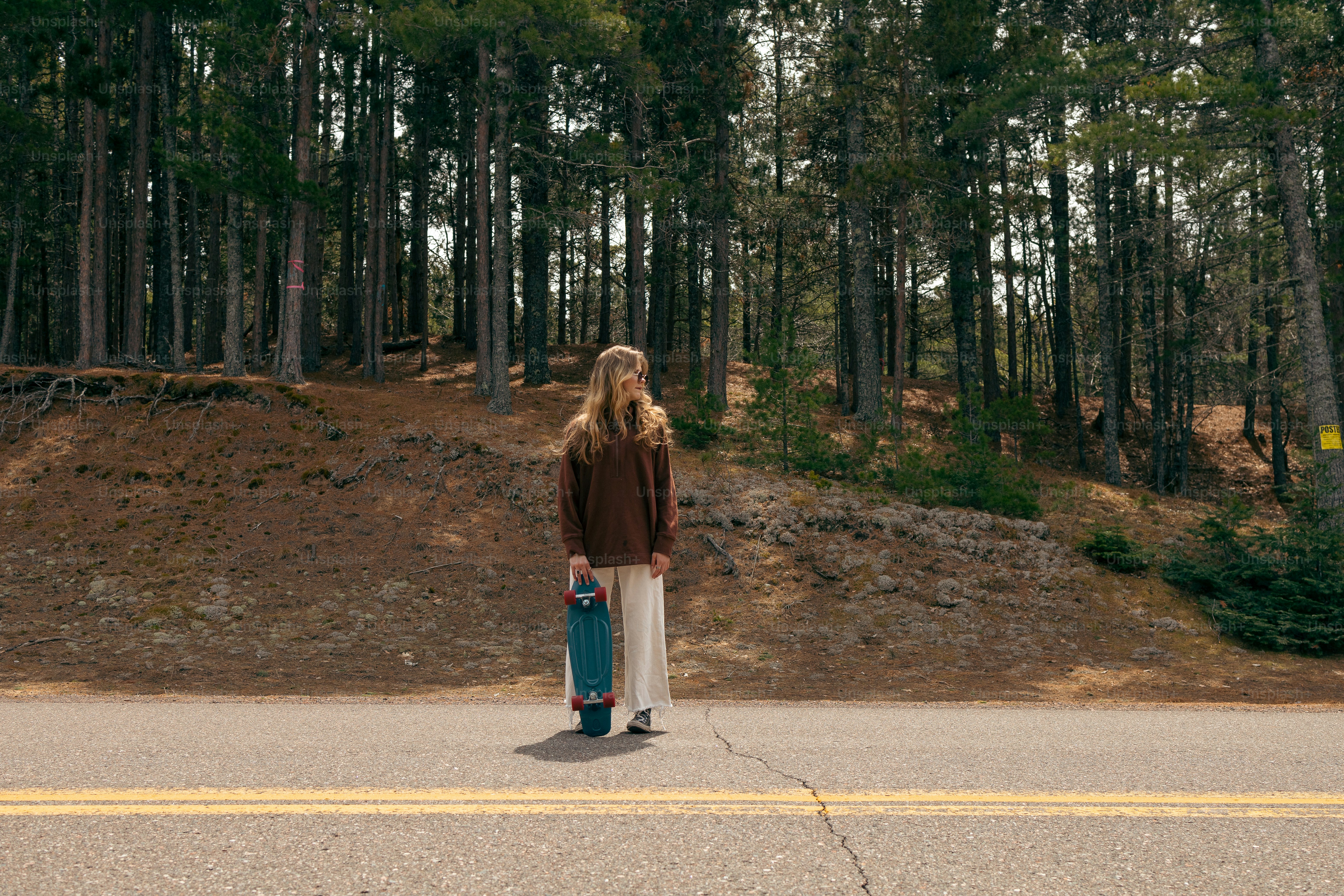 a woman standing on the side of a road holding a blue suitcase