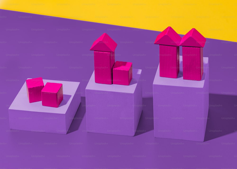 紫色のテーブルの上に座っている3つのピンクのブロックのグループ