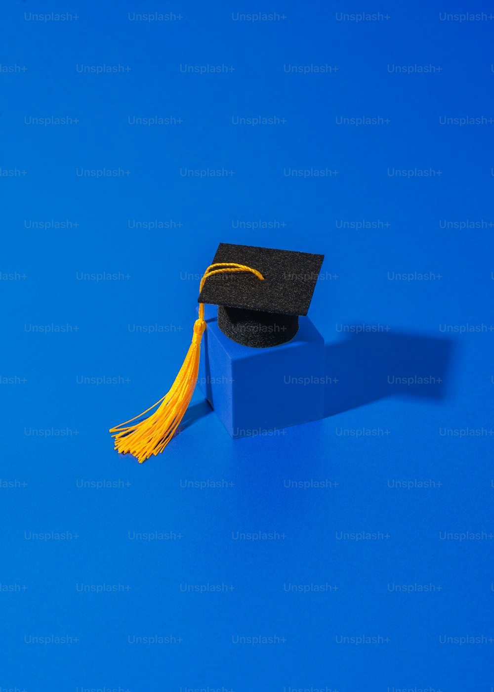 a graduation cap and tassel on a blue block
