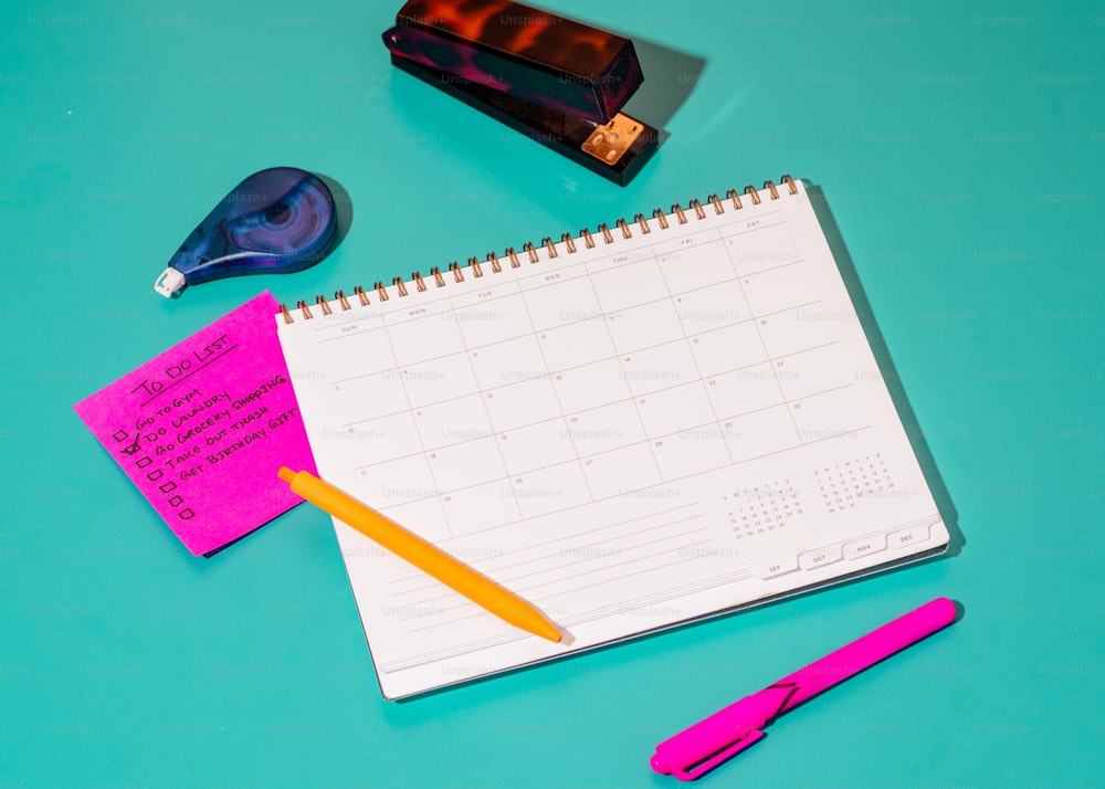 a desk with a calendar, pens, and a marker