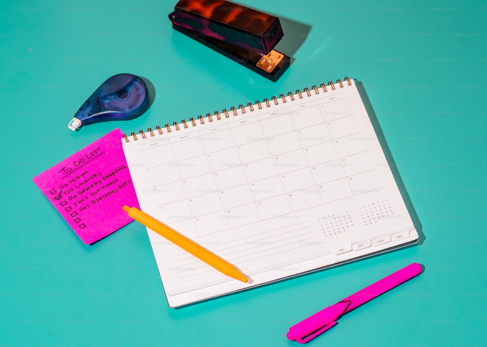 uma mesa com calendário, canetas e um marcador
