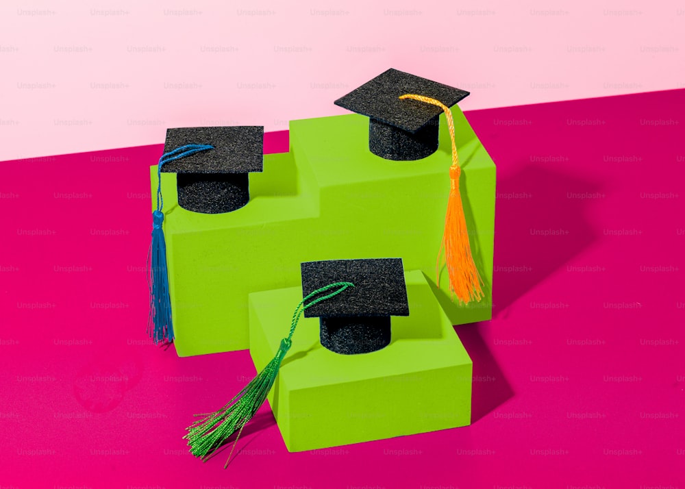 a pair of graduation caps sitting on top of green blocks