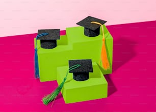 녹색 블록 위에 앉아 있는 한 쌍의 졸업 모자