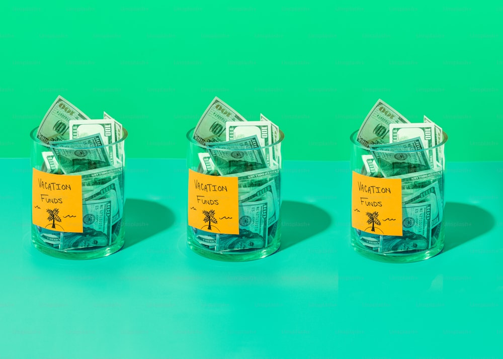 três frascos de vidro com dinheiro em cima de uma mesa