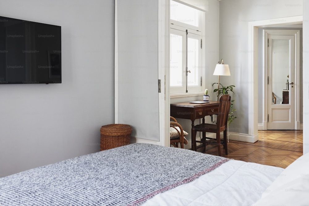 a bedroom with a bed, desk and television