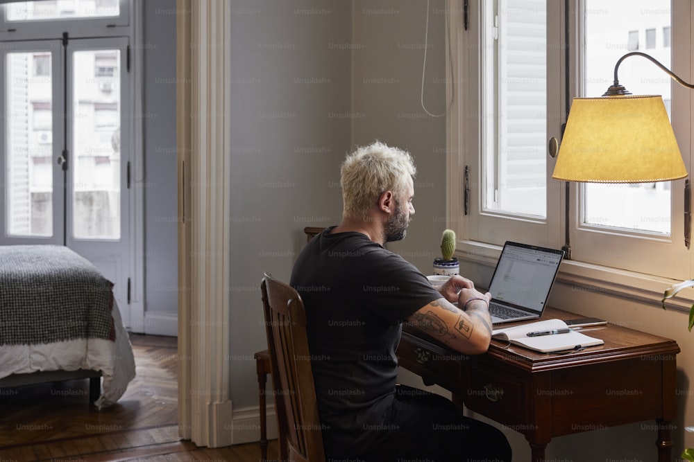 a man sitting at a desk using a laptop computer